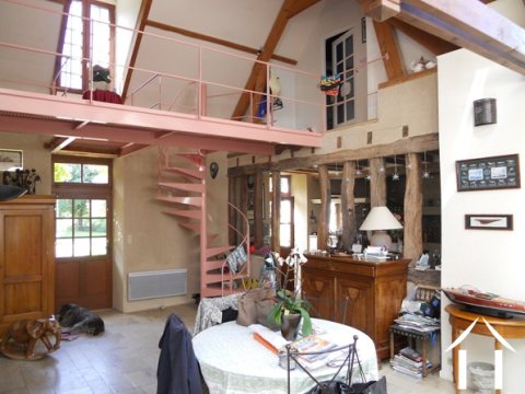 Het gewelfde deel van het woongedeelte  waarbij ook de keuken zichtbaar is (achter de staande oude eiken balken); het moderne portaal in de kamer waarlangs toegang  tot de twee slaapkamers boven wordt verkregen, alsmede tot het eetgedeelte aan het begin van deze moderne uitbouw, die haaks op deze indrukwekkende ruimte ligt..