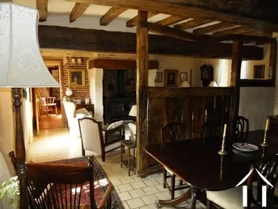 De lounge (40 m²) heeft een grote open haard, stenen muren met voegen, een eiken balkenplafond en veel karakter.