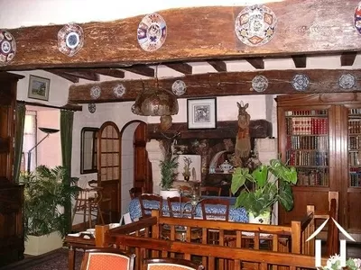 Door het gehele 500-jaar oude pand zijn zeer vele originele kenmerken te vinden, inclusief zichtbare eiken balken, stenen muren, indrukwekkende schouwen en vloeren met terracotta-tegels. Dit is een foto van de eetkamer met daarachter de keuken.