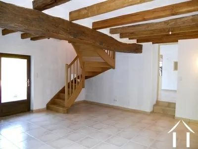 Woonkamer  met trap naar de ouderslaapkamer boven. De trapjes en de deur leiden naar het ander deel van het huis.