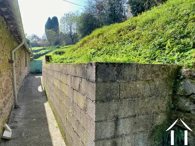 Le mur de soutènement en parpaings. Au fond, la porte vers le chemin d'accès